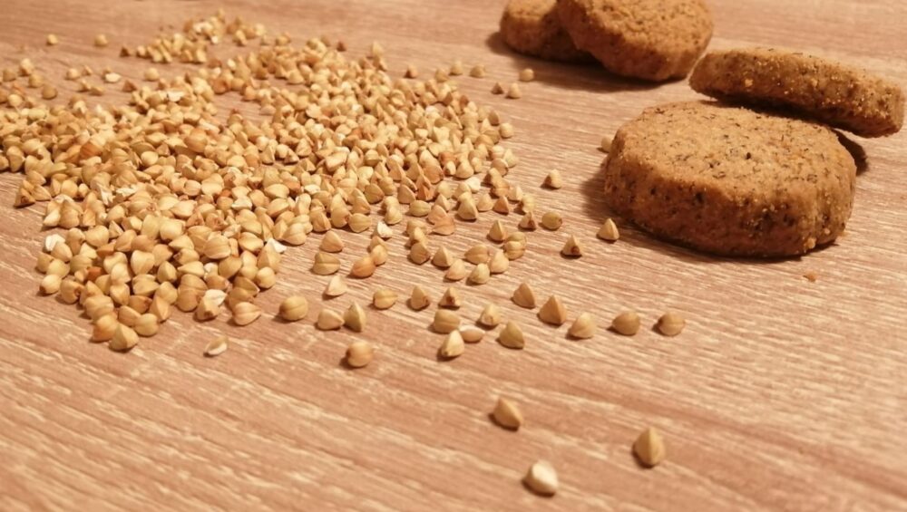 chicchi di grano saraceno e frollini appoggiati su tavolo in legno